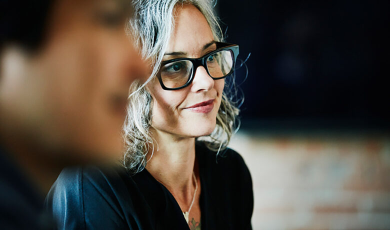 A smiling woman with curly hair in a meeting
