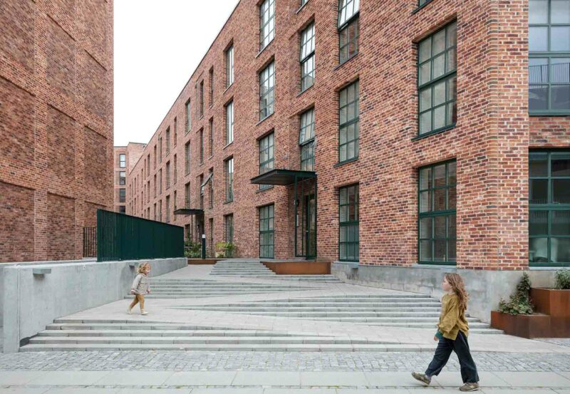 Two young girls walking in between brick houses in the urban district Grønttorvet in Copenhagen