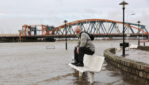 Active senior keeping his feet dry in the flooded street at the river bank of the city "Zutphen" in the Netherlands
