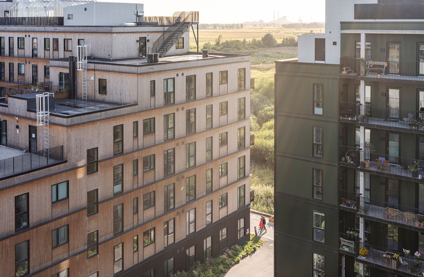 Modern apartment buildings with balconies and large windows, located in a green urban area.