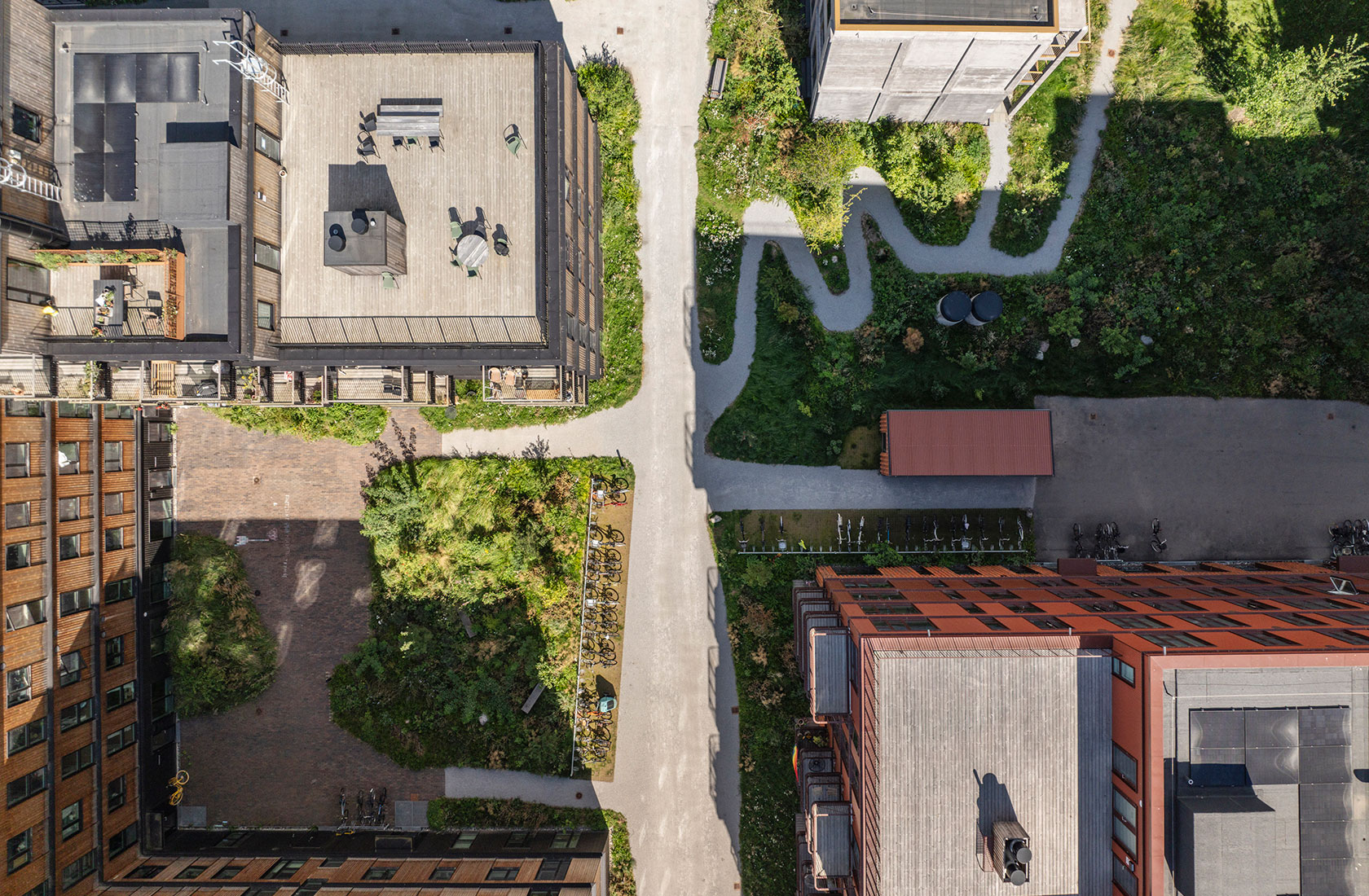 Aerial view of urban buildings with rooftop terrace, paved walkways, and green garden areas.