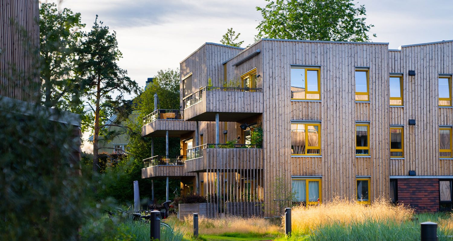 A residential building of wood sourounded by greenery.