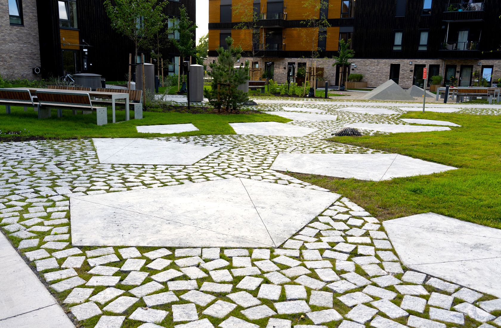 Landscape architecture with cobblestones, grass and big grantie blocks.