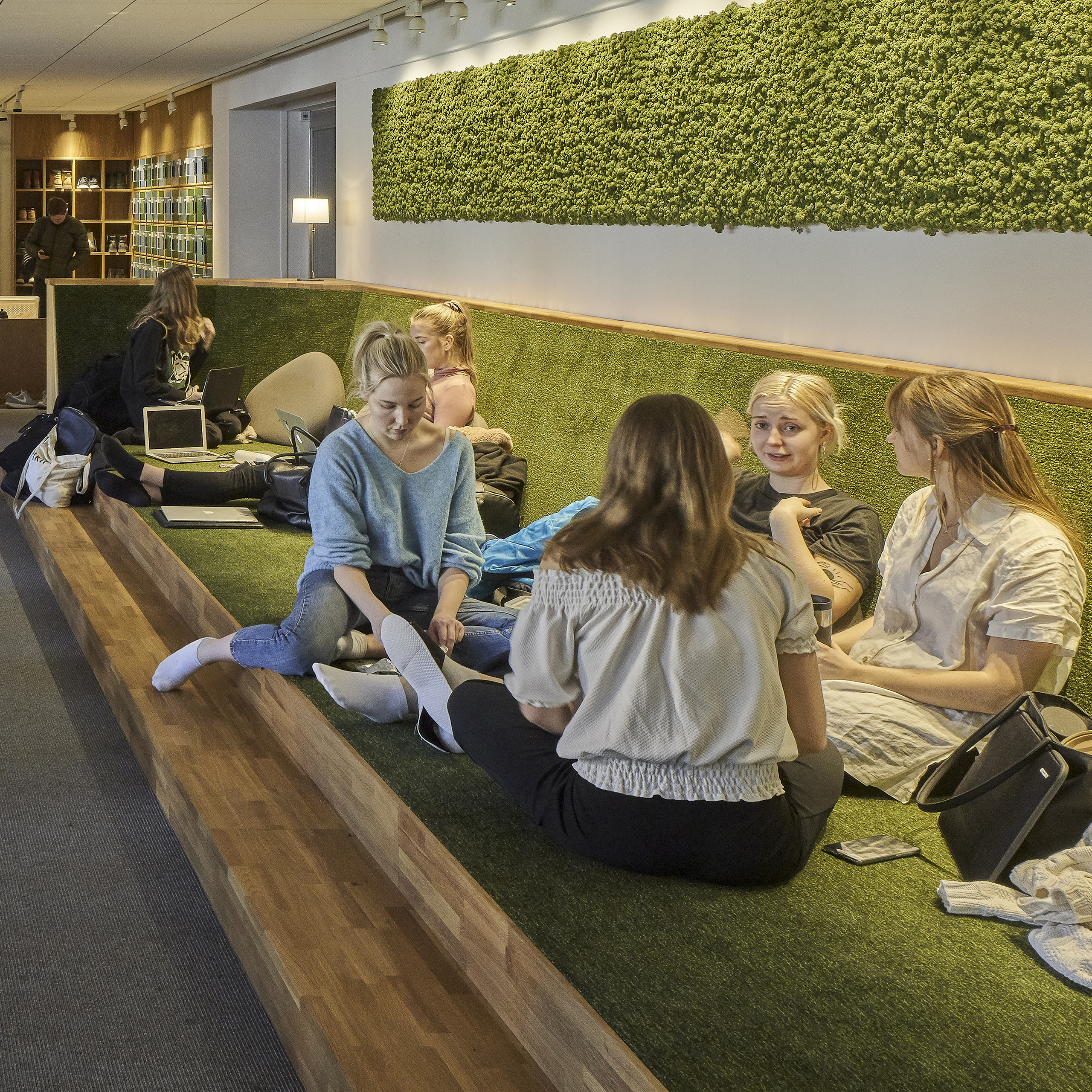 A green study space with students sitting in a sofa in Ekonomikum at Uppsala University