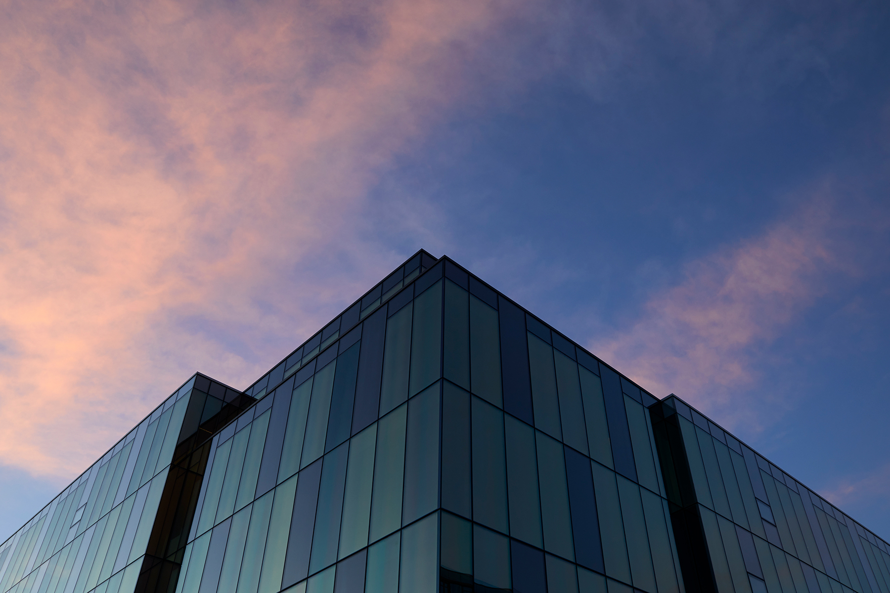 Glass facade of office building and a blue sky in the background.