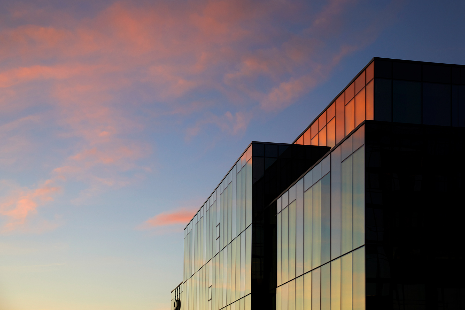 Officebuilding with glass facade with the sun set mirrored in the glass