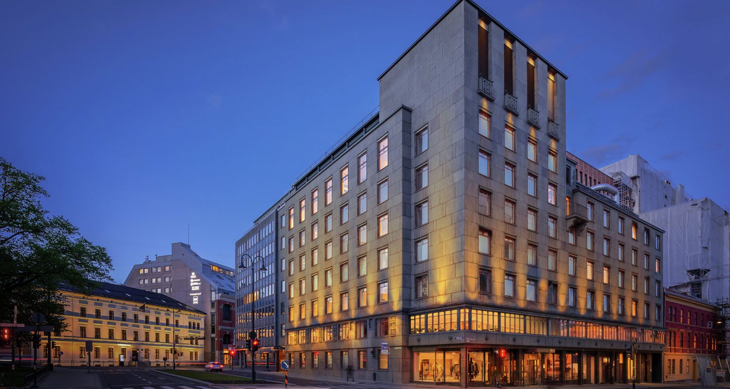 Facade of an old office building in stone in the evening with a dark blue sky.