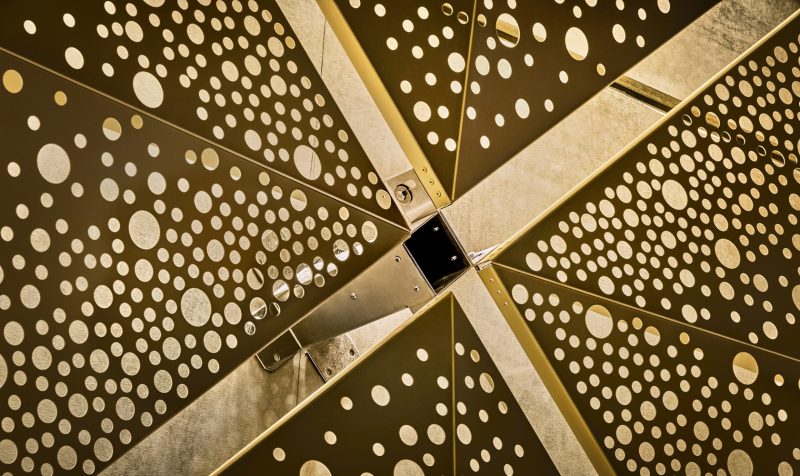 Close up of metal elements in gold with a pattern of holes.
