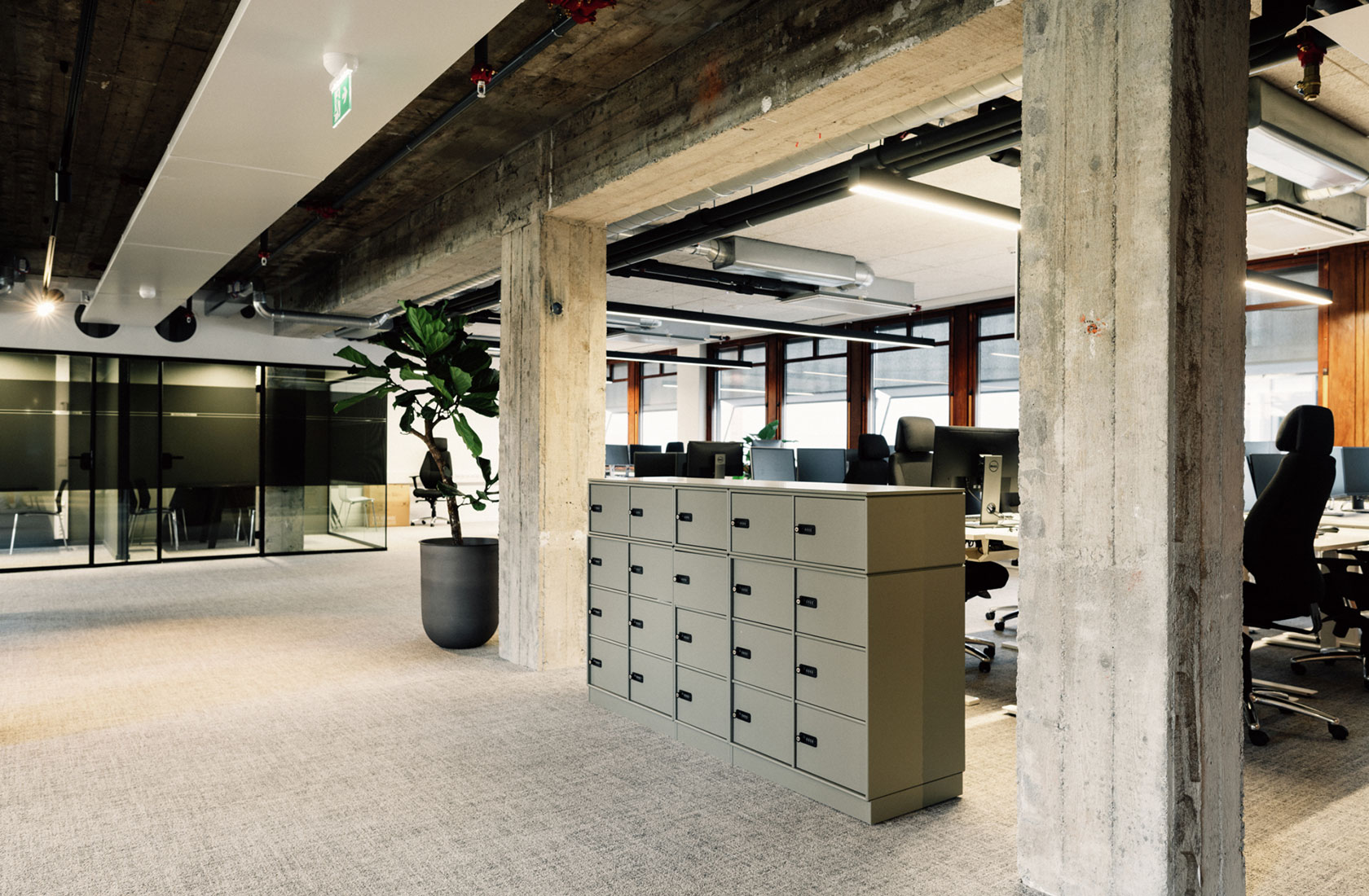 Office space with pillars of concrete a storage cupboard in grey in front of a landscape with workplaces.