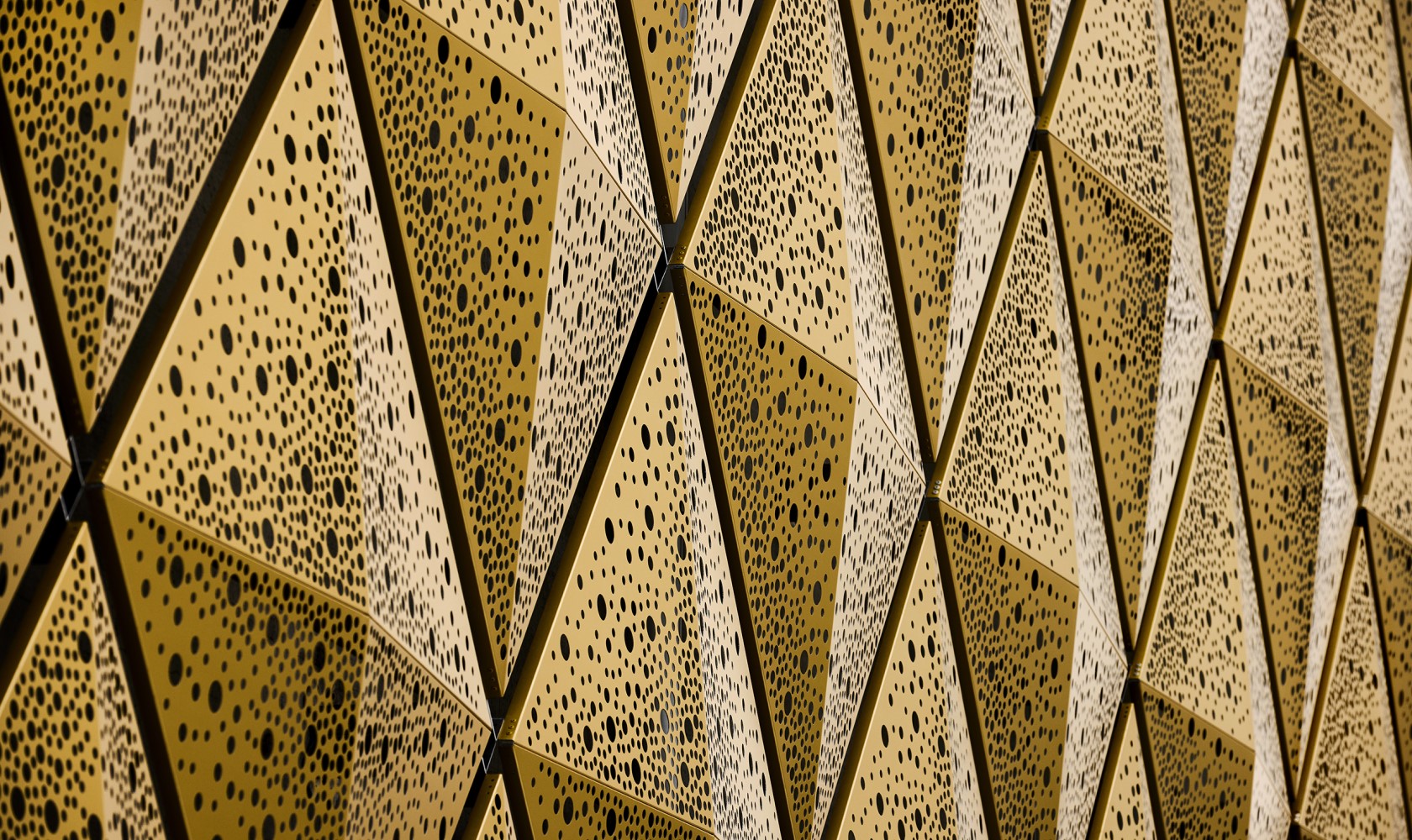 Close up of metal elements in gold with a pattern made of holes.