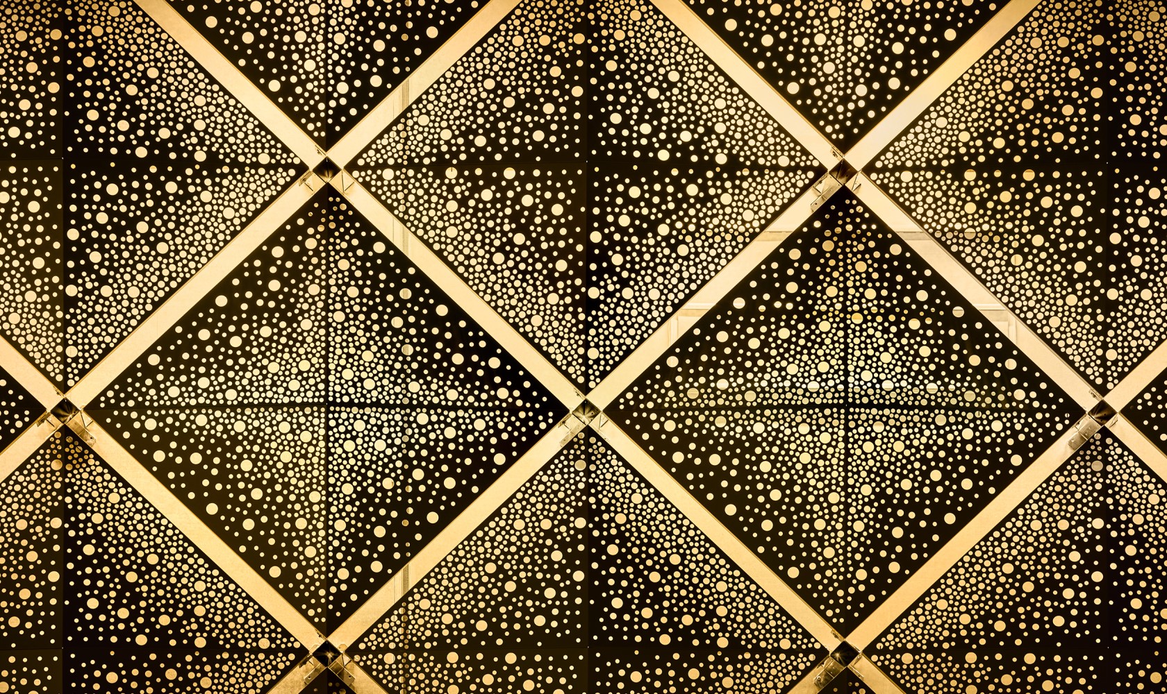 Close up of square metal elements in gold with a pattern of holes.