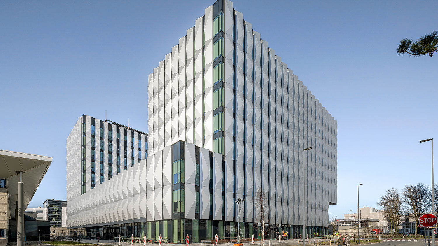 Corner view of an office building, with facade elemtnts in white.