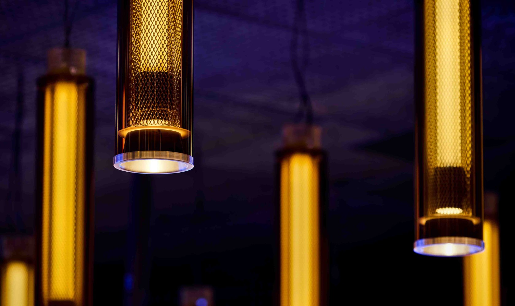 Close up on the light sources that resemble golden rods in the ceiling of the auditorium