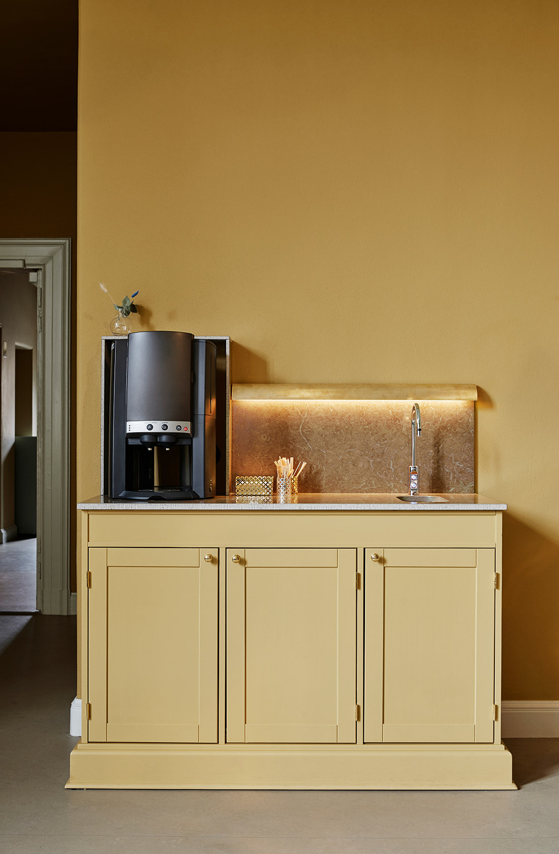 Coffee station in ocher in front of a wall painted in the same color.