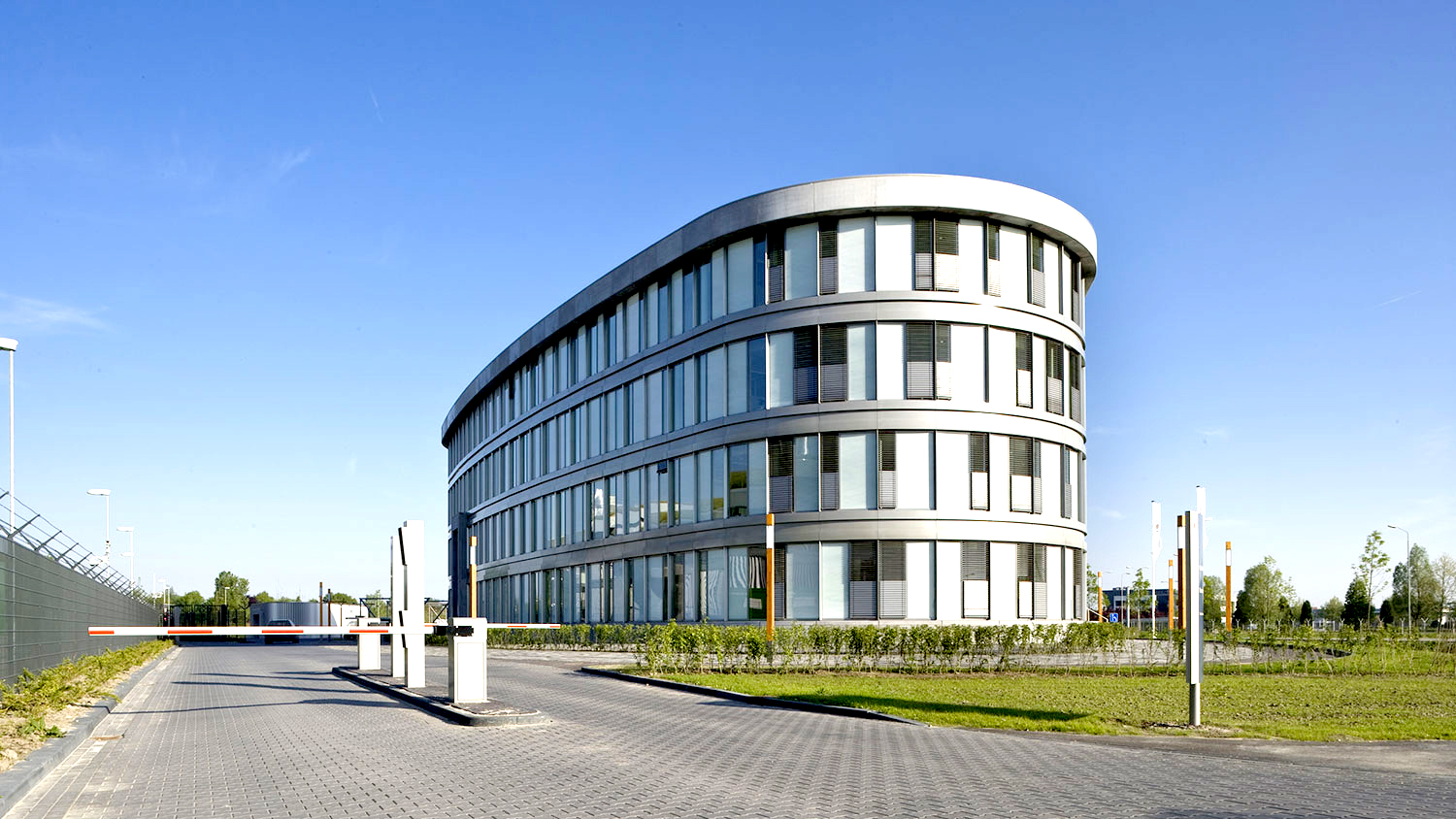 Organic-shaped four-story office building with a white facade and large window areas.