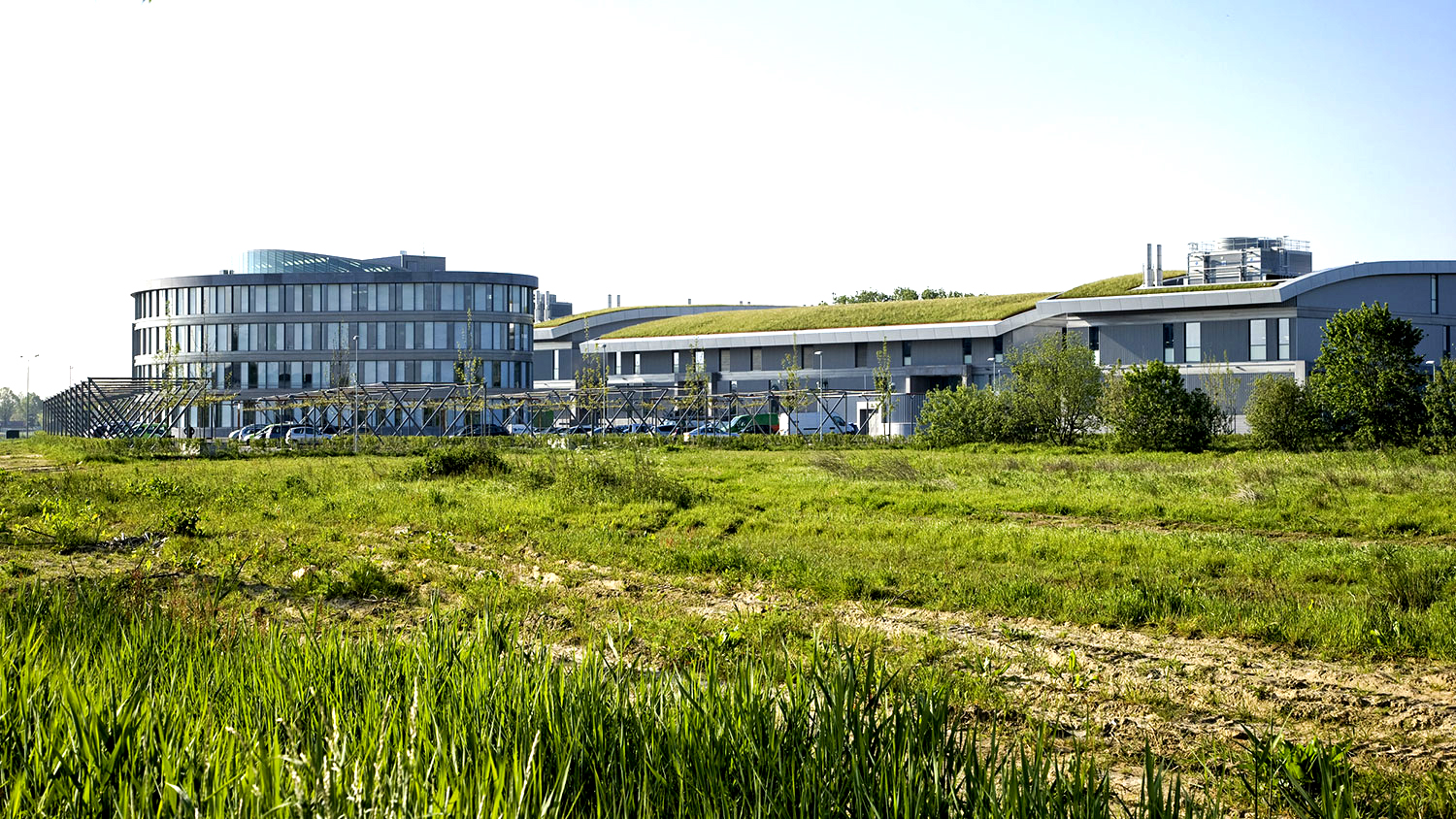 Green areas with grass and bushes in the foreground. The data center with offices can be seen in the background.