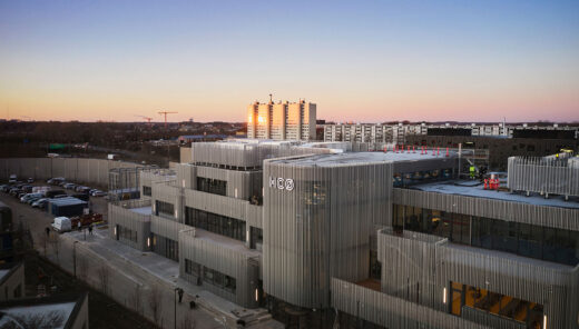 From above, the entire school building can be seen with its surrounding buildings. The building consists of several parts of rounded units on multiple levels. The facade is covered with vertical aluminum battens.