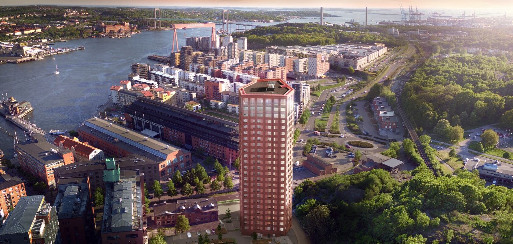 Cityscape from above with a narrower 26-story high-rise building in red brick. Behind the building, you can see a larger area with residential buildings located near the inlet towards Gothenburg.