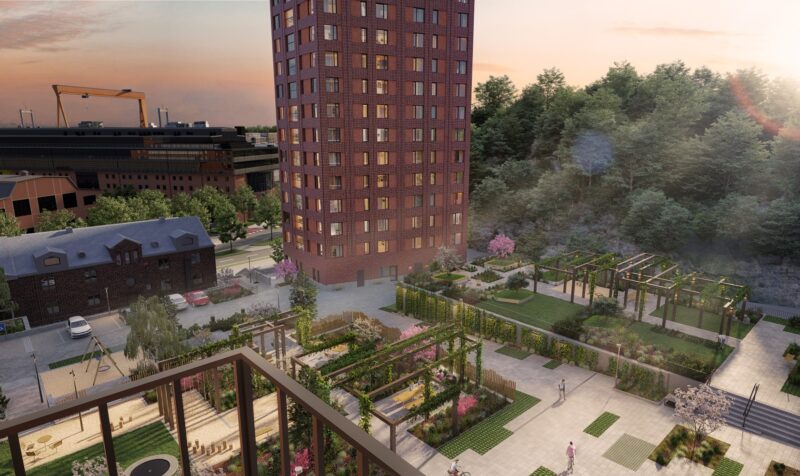 View showing the lower floors of the 26-story high-rise residential building in red brick. A park-like area with stone paving, plantings, and trellises is located in front of the building.