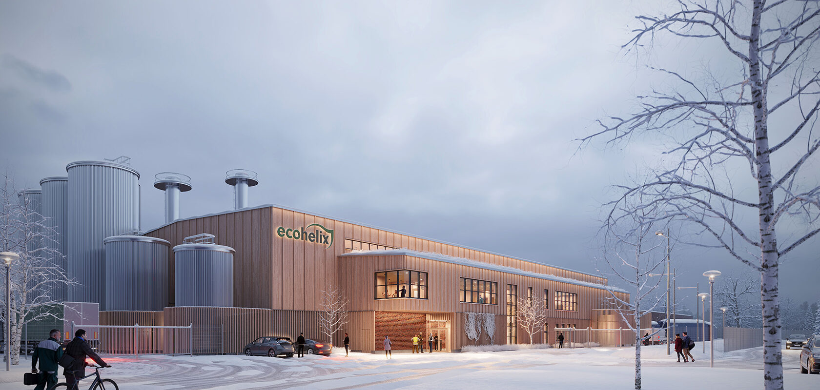 Visualization showing a winter scene of an industrial building in light wood with gray silos on the left. A lower section with windows extends along the long side of the building. In front of the building, there is a road with a few birch trees on the side.