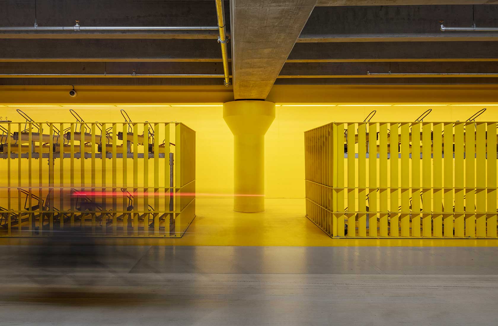 A two-level bike rack in a parking garage with yellow walls.