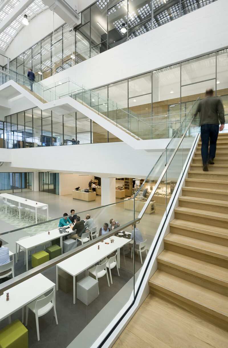 Person moving up an open staircase in a modern office building with bright interior and a large amount of light.