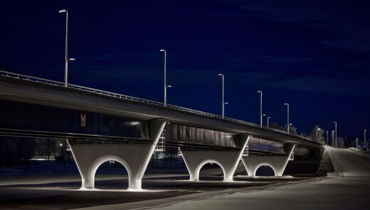 Evening view of motorway bridge seen from the side in winter landscape with illuminated bridge arches.