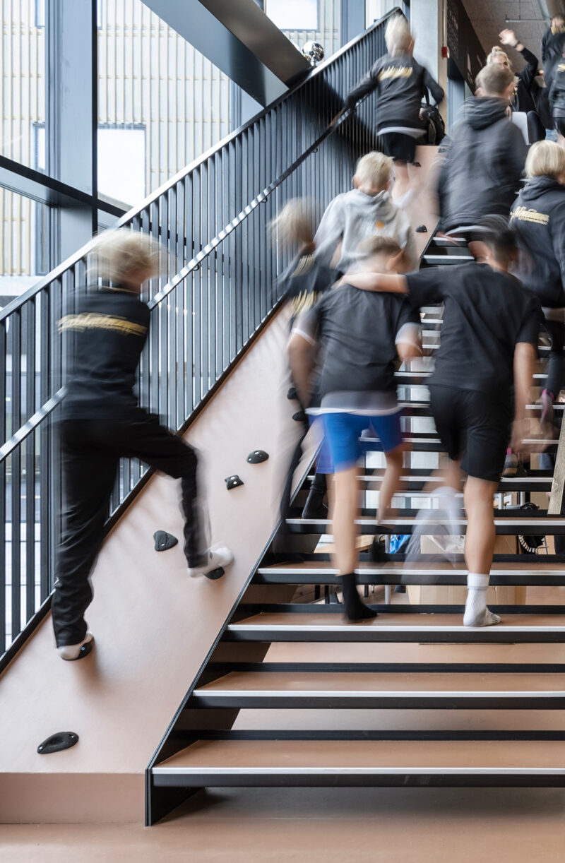 Several teenagers running up a staircase in a larger building.