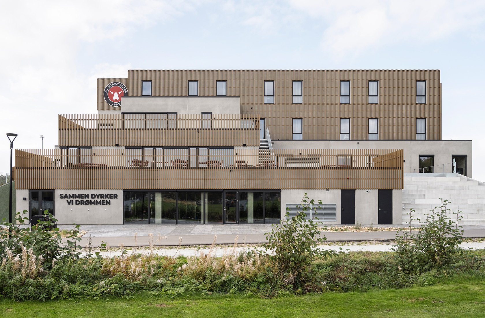 School building with four floors in concrete and parts of the façade with vertical wooden paneling.