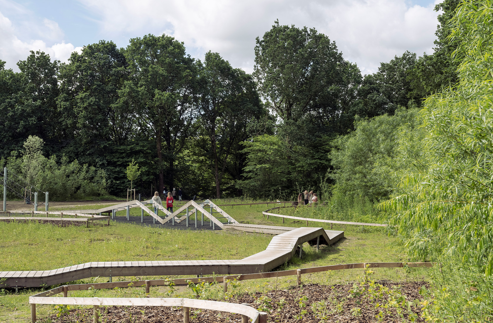 Part of a playground in a green area with wooden pathways resembling walkways.