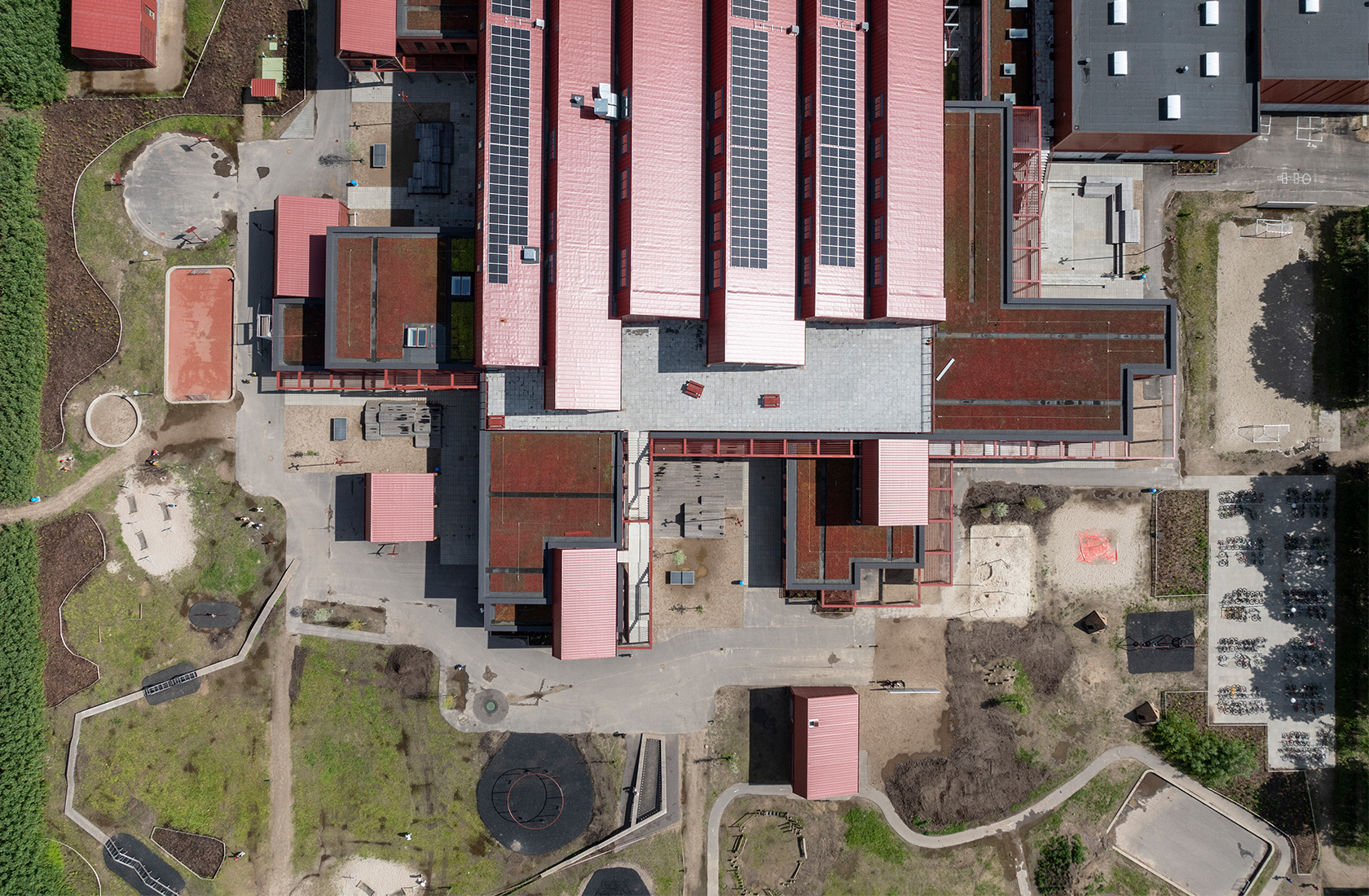 Aerial view of a school complex in red with solar panels on some parts of the roofs.