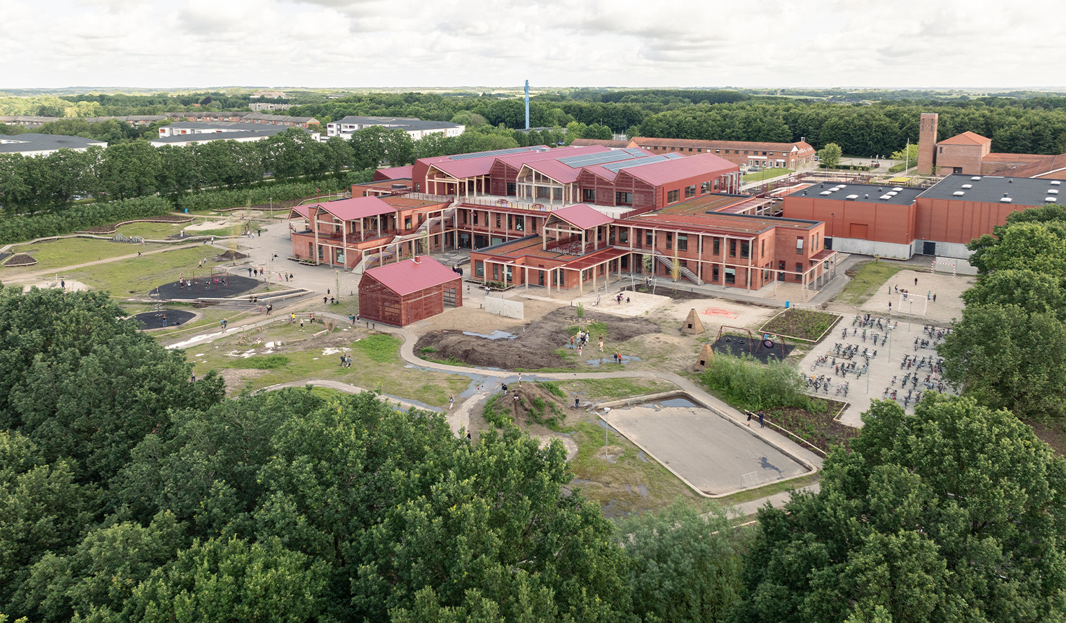 Image taken from above at an angle of a school made up of various buildings in red brick.