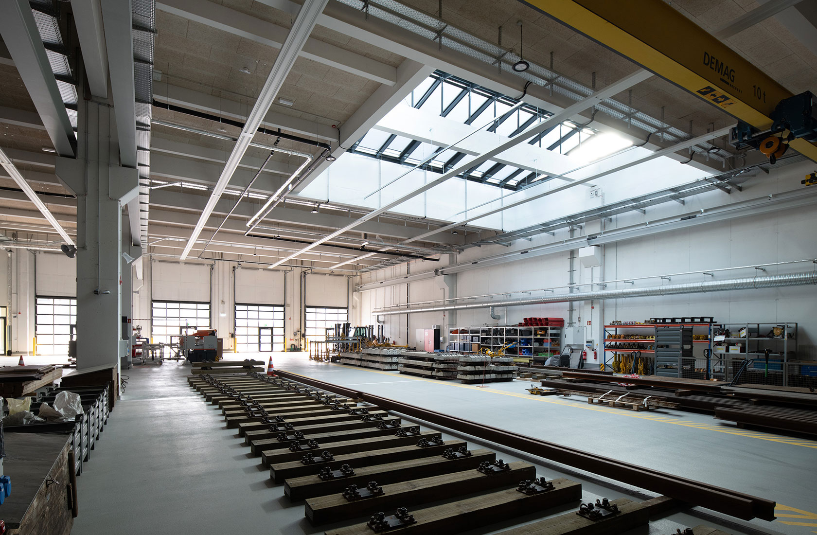Modern workshop with a cement floor and bright walls with train tracks on the floor.