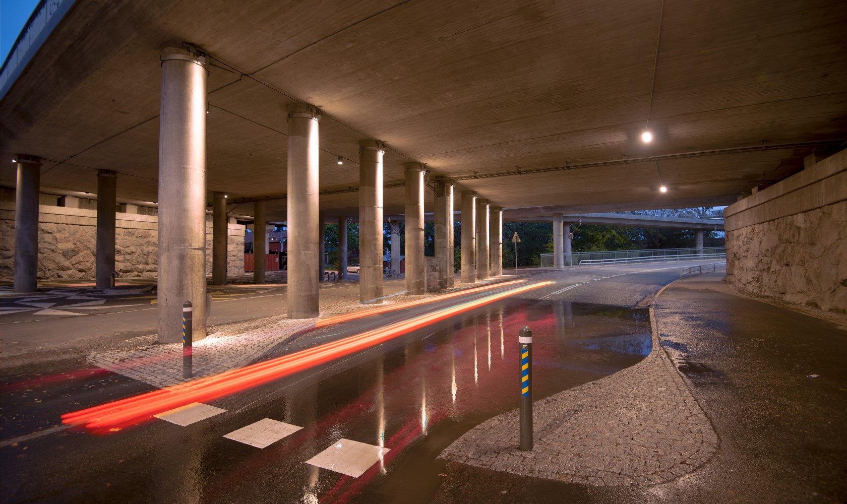 Nicely lit walkway under a bridge.