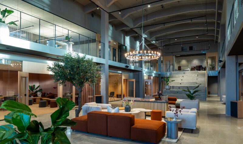 Lounge area with high ceilings and a conference room in the background on the lower level, and workspaces on the upper level.