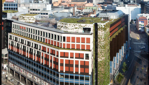 Image from above of a larger building in central Oslo that partially has a green facade and a large rooftop terrace with many green features.