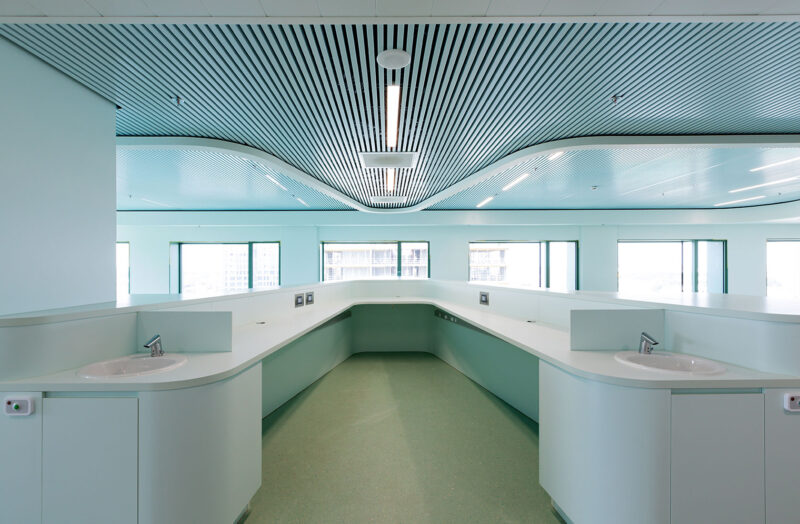 Interior image from an empty hospital building with a U-shaped desk with sinks on the sides.