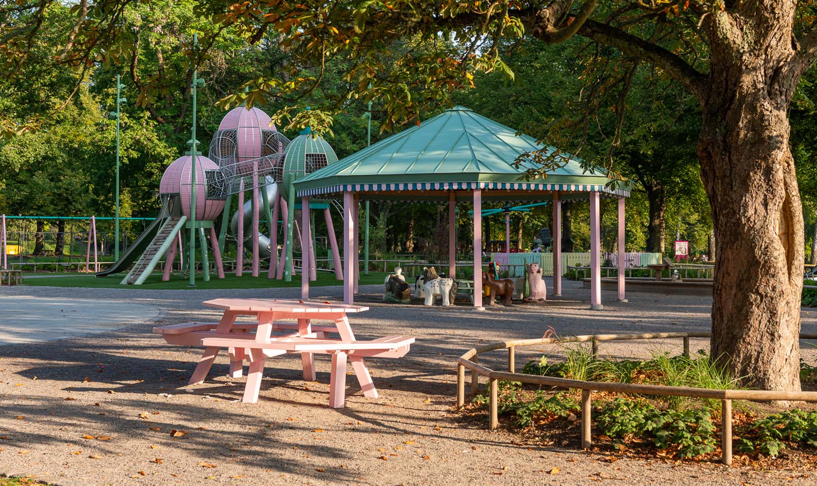 Tivoli-inspired playground in a green area with seating areas in the foreground.