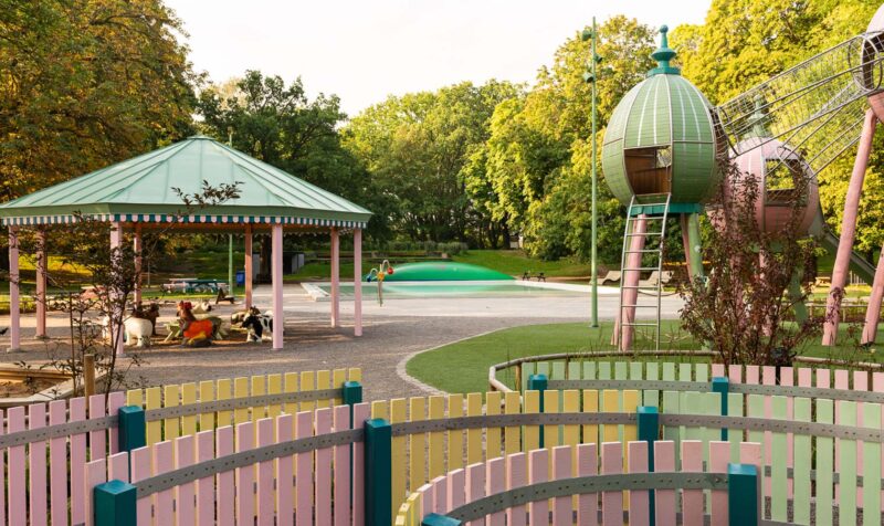 Playground area in a park with a pool in the background.