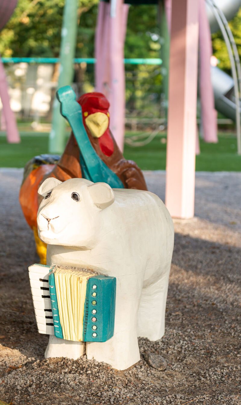 Close-up of wooden sculptures of animals in the playground area.