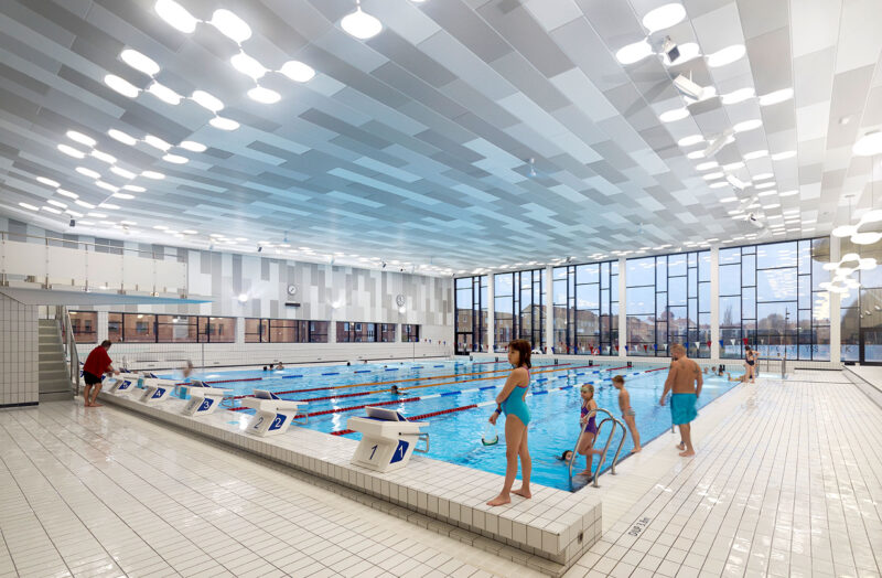Swimming hall with lanes for competitive or exercise swimming with many visitors.