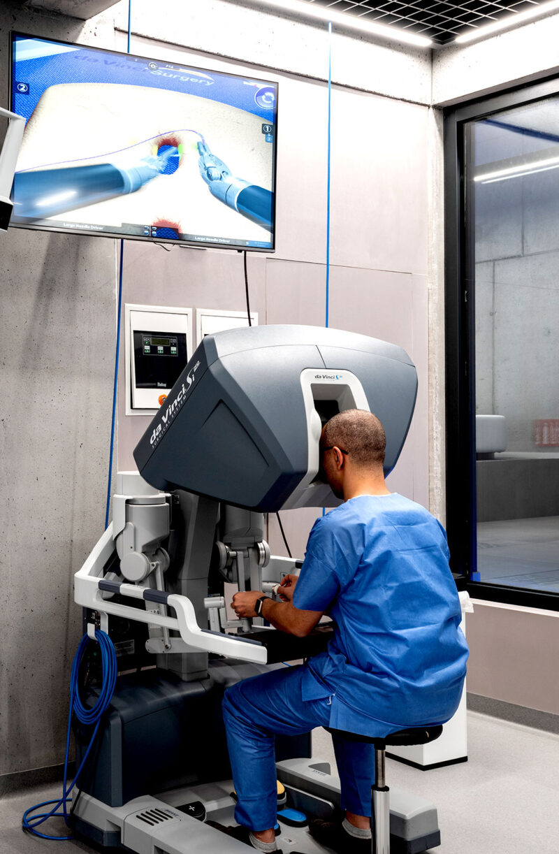 Surgeon operating a da Vinci robotic surgical system with monitor displaying procedure.