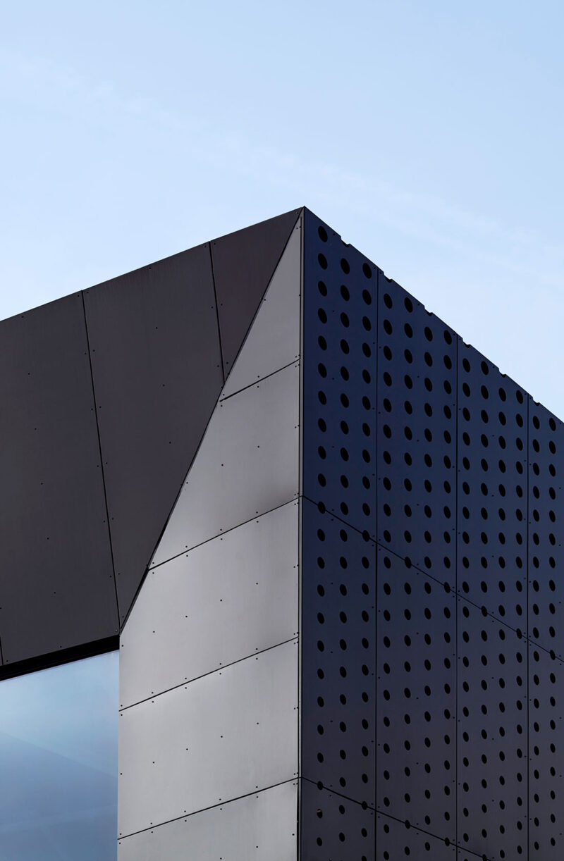 Corner section of the facade of a larger building in black metal.