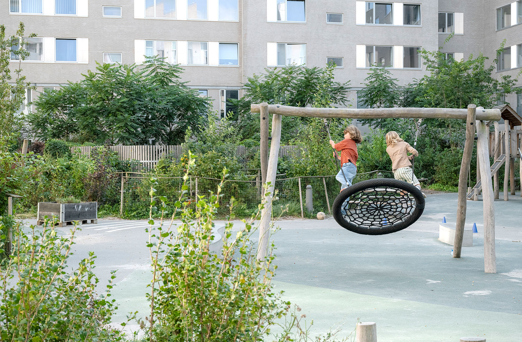 Two children on a larger swing on a playground.