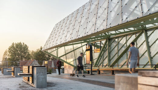Modern train station platform with people walking and benches, during sunset.