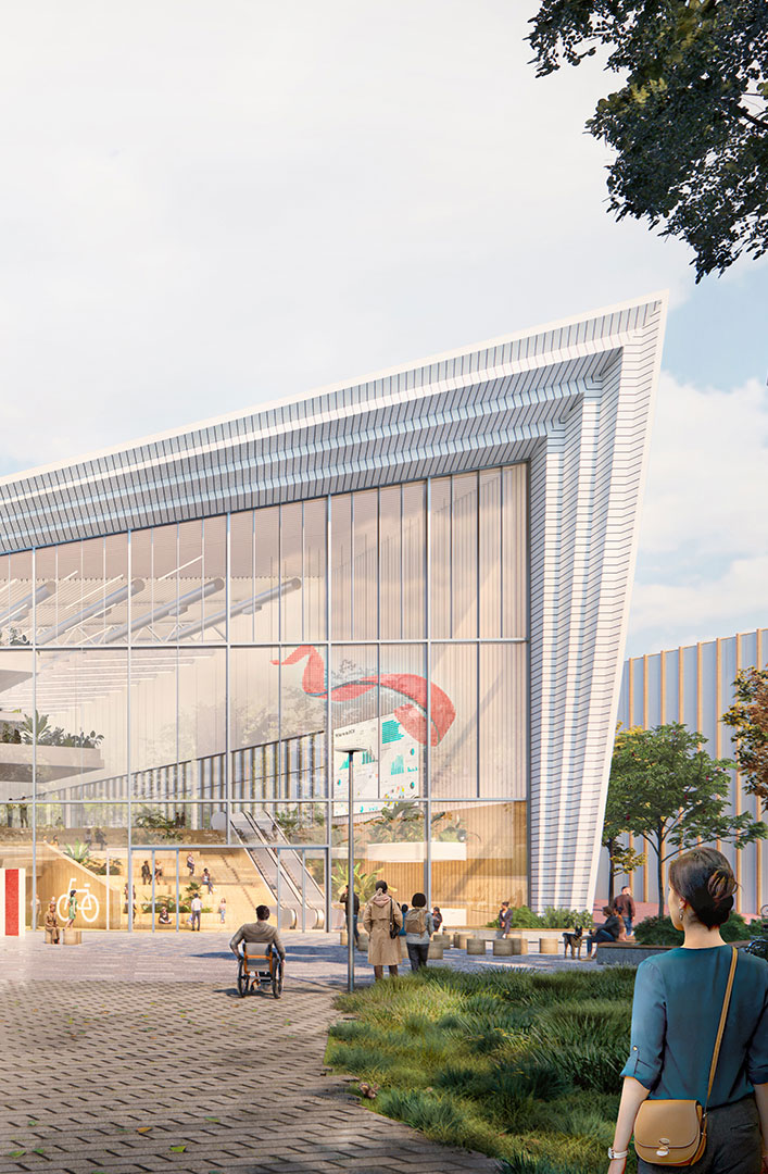 Modern glass-building entrance with people, including a person in a wheelchair and lush greenery.