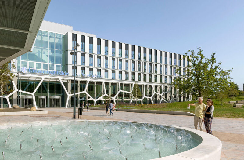 Leiden University Faculty of Science building with a fountain in front and people walking nearby.