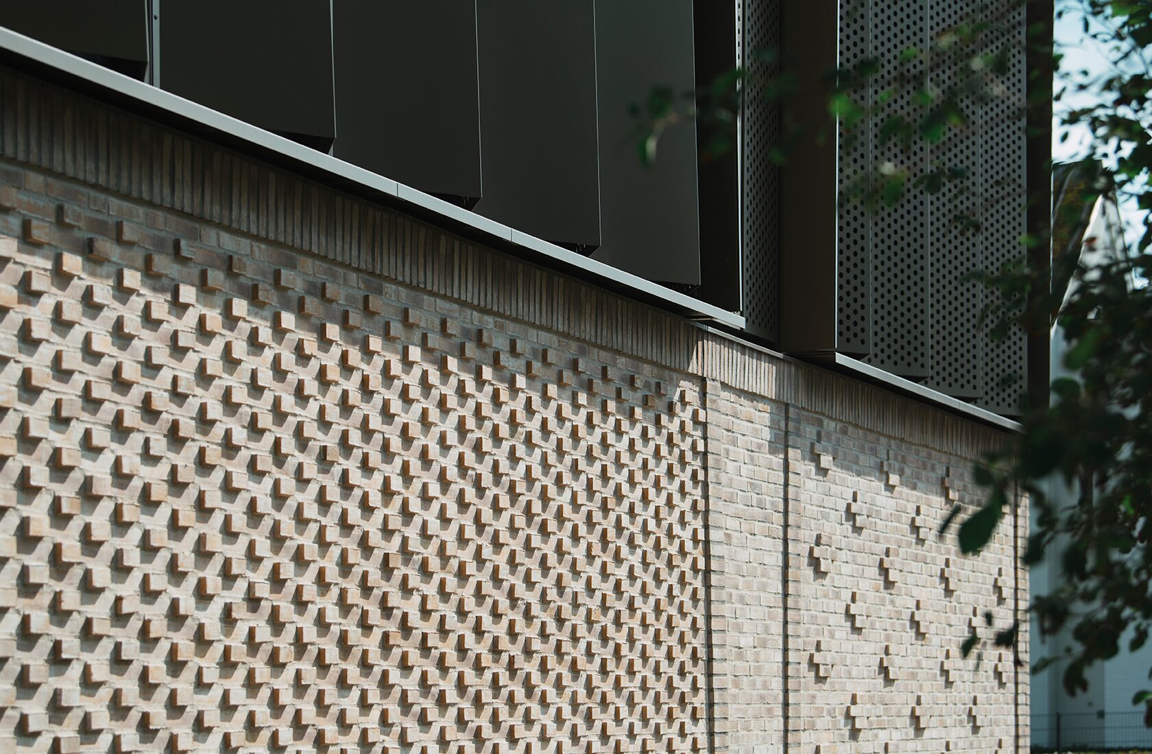 Modern building facade with textured brick wall and dark metal panels