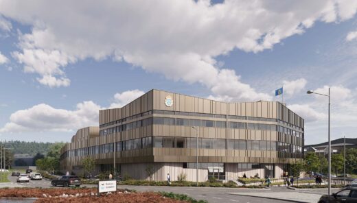 Modern police office building with beige panels, surrounded by cars and pedestrians, under a blue cloudy sky.