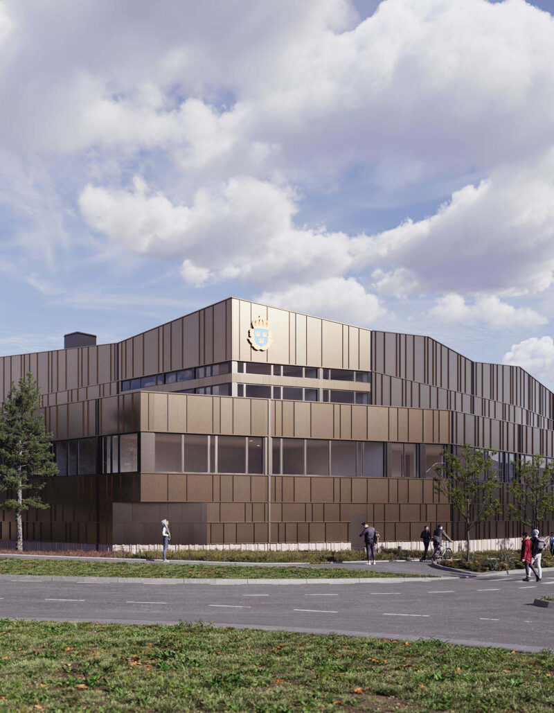 Modern building exterior of police station with bronze panels and people walking, under cloudy sky.
